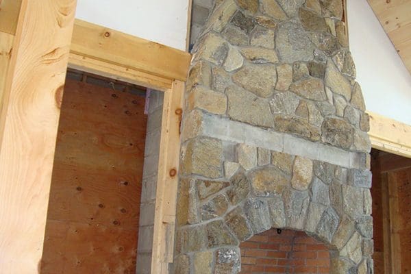 A Stone fireplace that reaches to the top of a vaulted ceiling.
